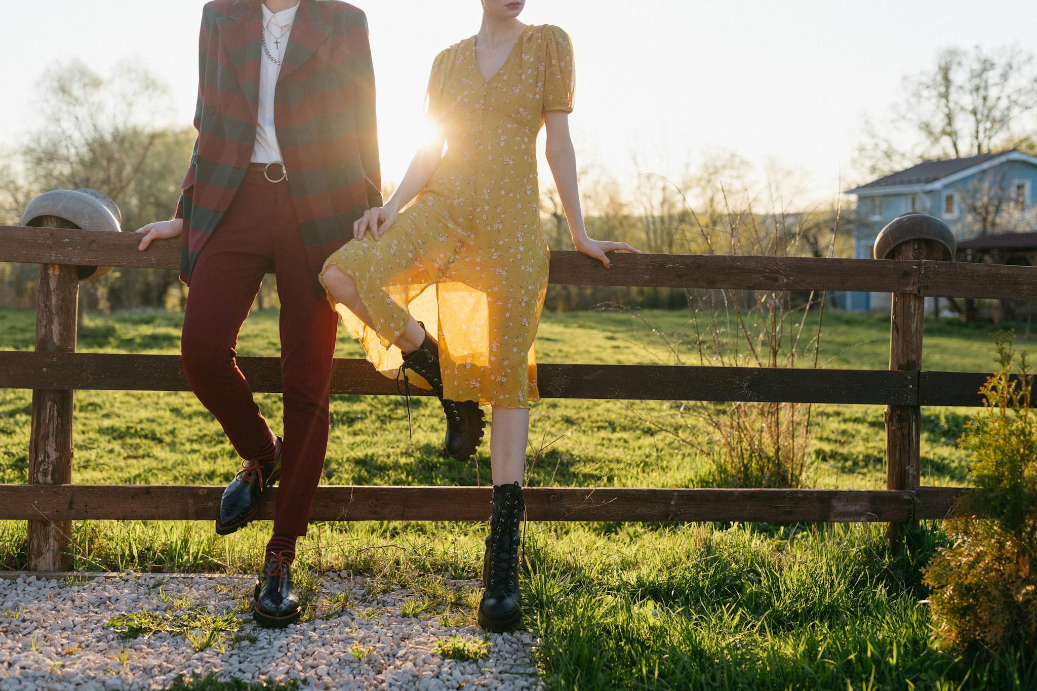 Couple posing stylishly outdoors in sunlight, showcasing modern fashion.