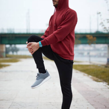 Athletic sporty man training in hoodie sweatshirt in urban city park.