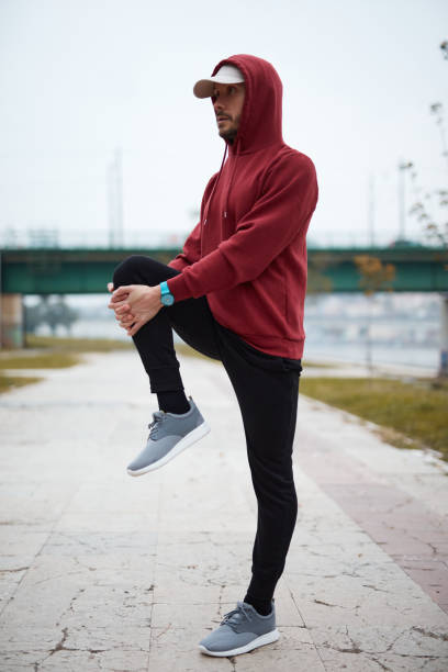 Athletic sporty man training in hoodie sweatshirt in urban city park.