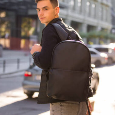 Tourist man with leather backpack in a city